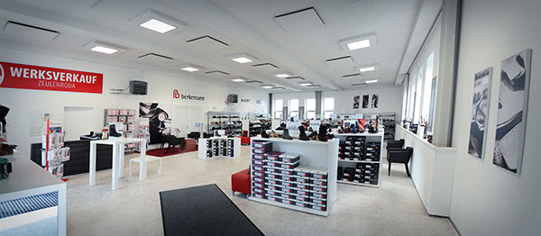 Innenansicht des Werksverkaufs in Zeulenroda mit Regalen voller Schuhkartons, Sitzgelegenheiten und Verkaufstheken.