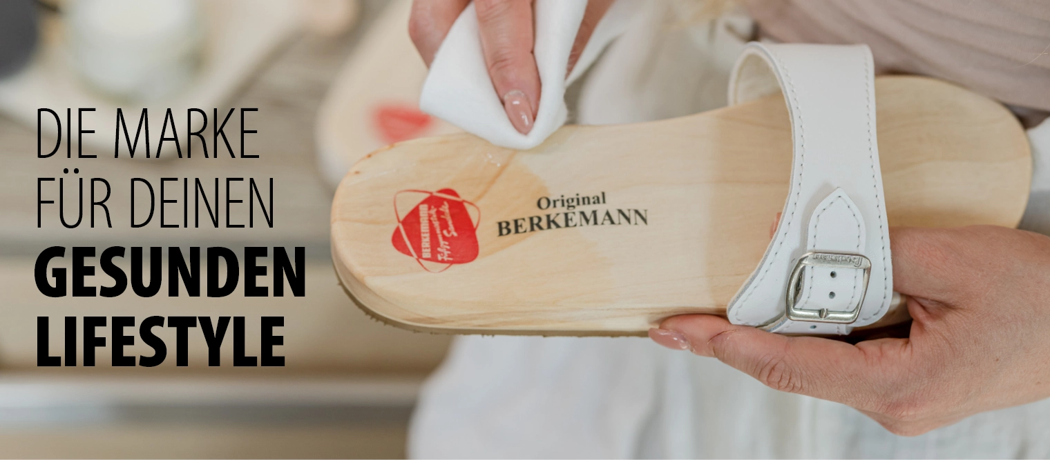 Frau pflegt eine weiße Berkemann Original Sandale mit einem Tuch und Pflegemittel.