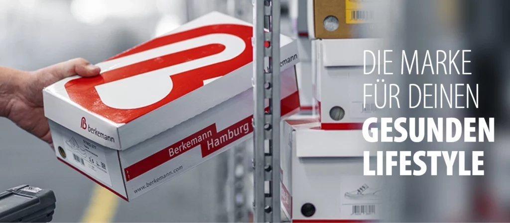 Hand nimmt einen Berkemann-Schuhkarton aus einem Regal im Warenlager, daneben ein Handscanner.