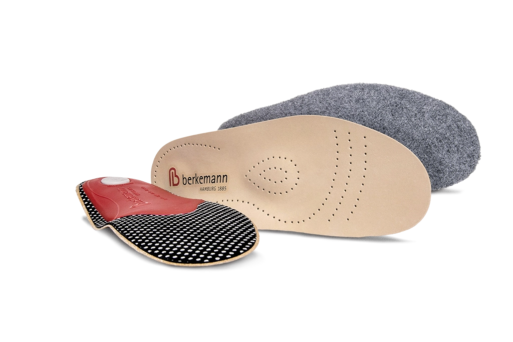 Drei Berkemann-Einlagen: vorne eine Einlage mit gepunkteter Unterseite und Pelotte, dahinter eine anatomisch geformte Leder-und Filz-Einlage als Wechselfußbett.