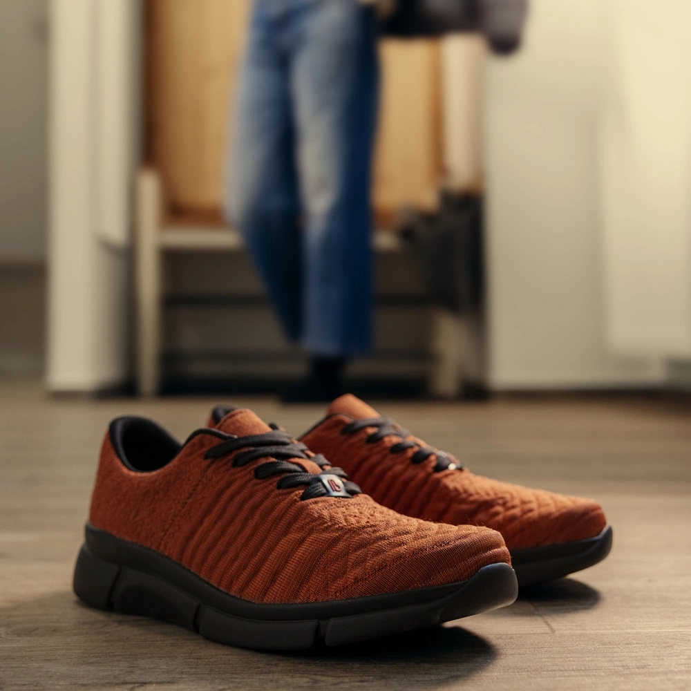 Berkemann Sneaker Pinar aus rotem Strick, Seitenansicht schräg von vorn, auf hellem Holzboden im Wohnraum platziert.